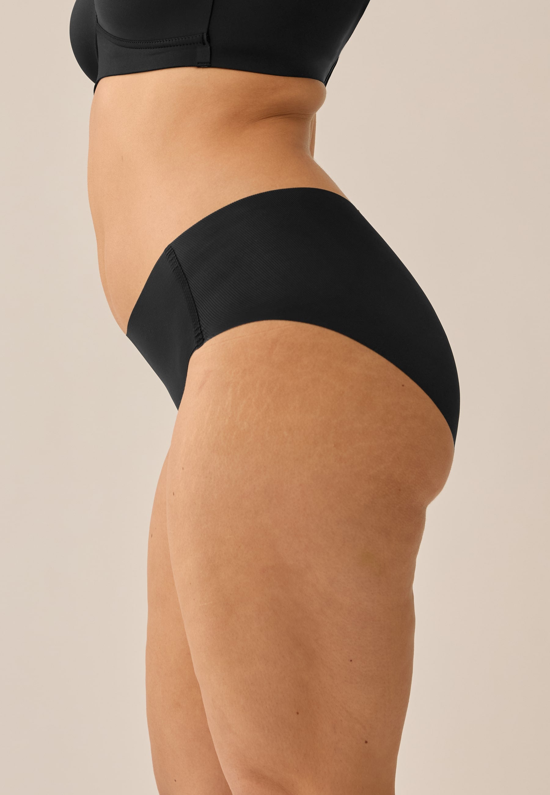 Model trägt NATURANA Everyday Slip und BH in der Farbe schwarz, stehend in Seitenansicht/Nahaufnahme