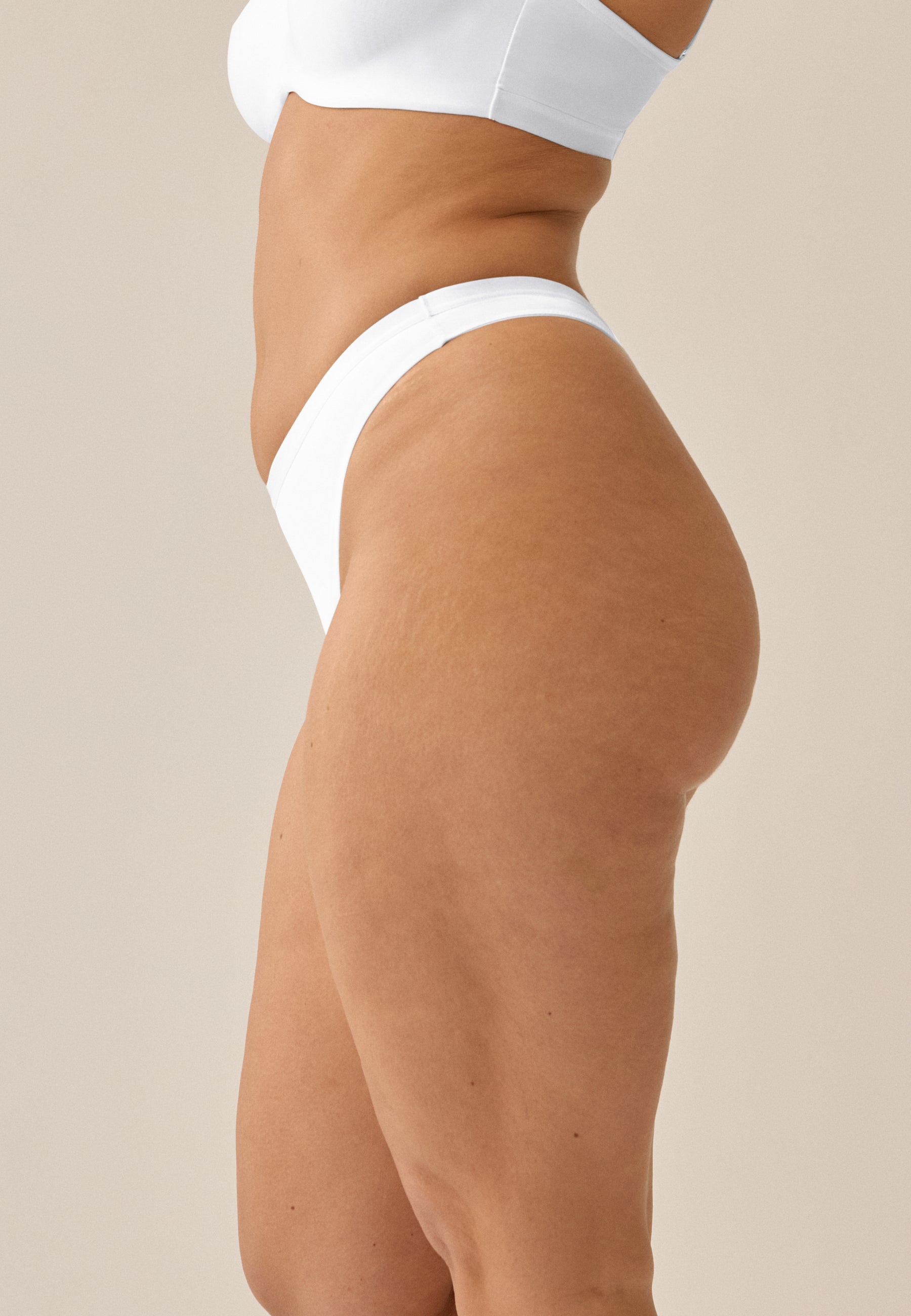 Model steht im Seitenprofil in NATURANA BH mit Bügel und String in der Farbe weiß
