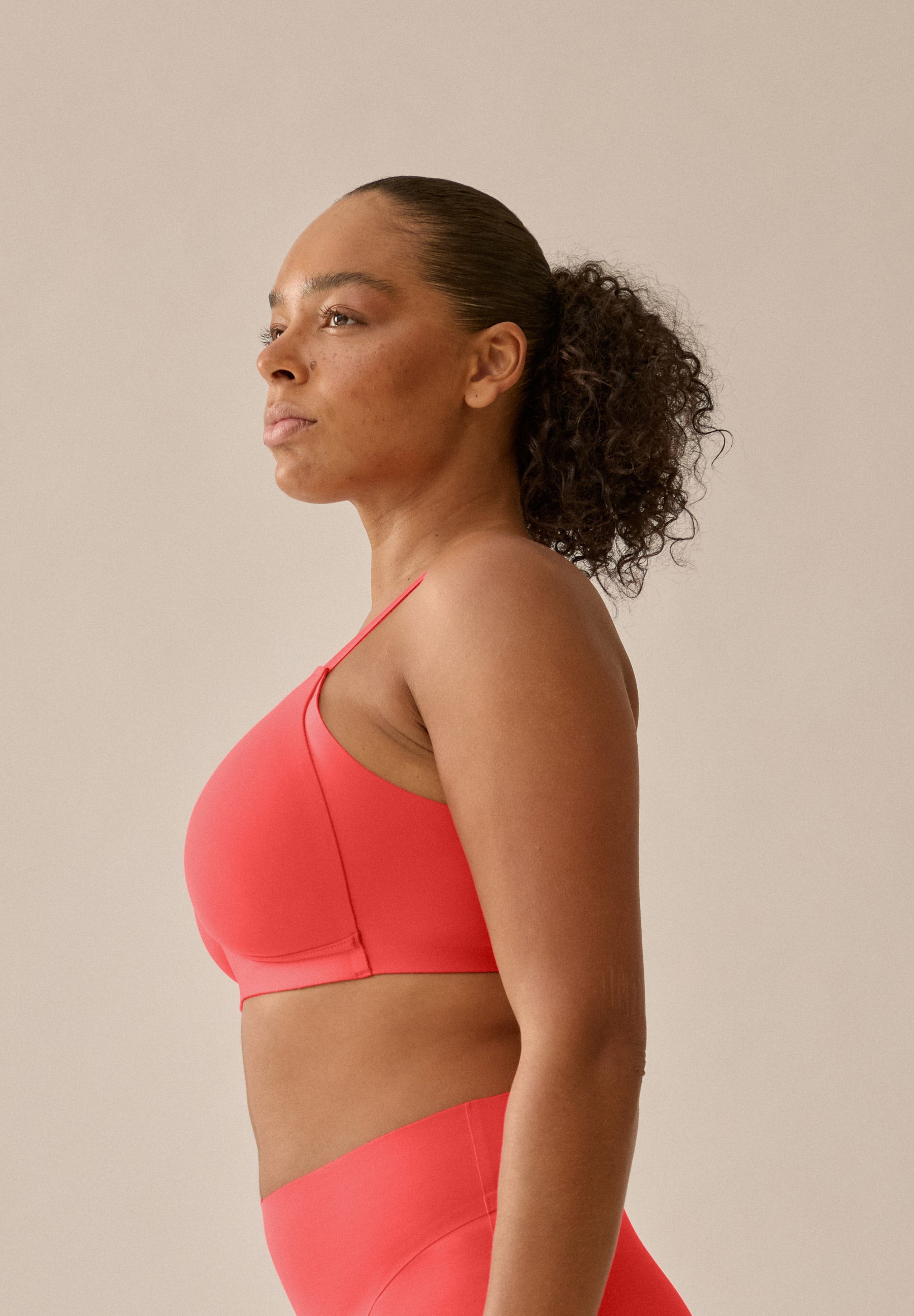 Das Model trägt den Sidesmoother-BH und -Slip von Naturana in der Farbe Chayenne Red mit einem Blick von der linken Seite