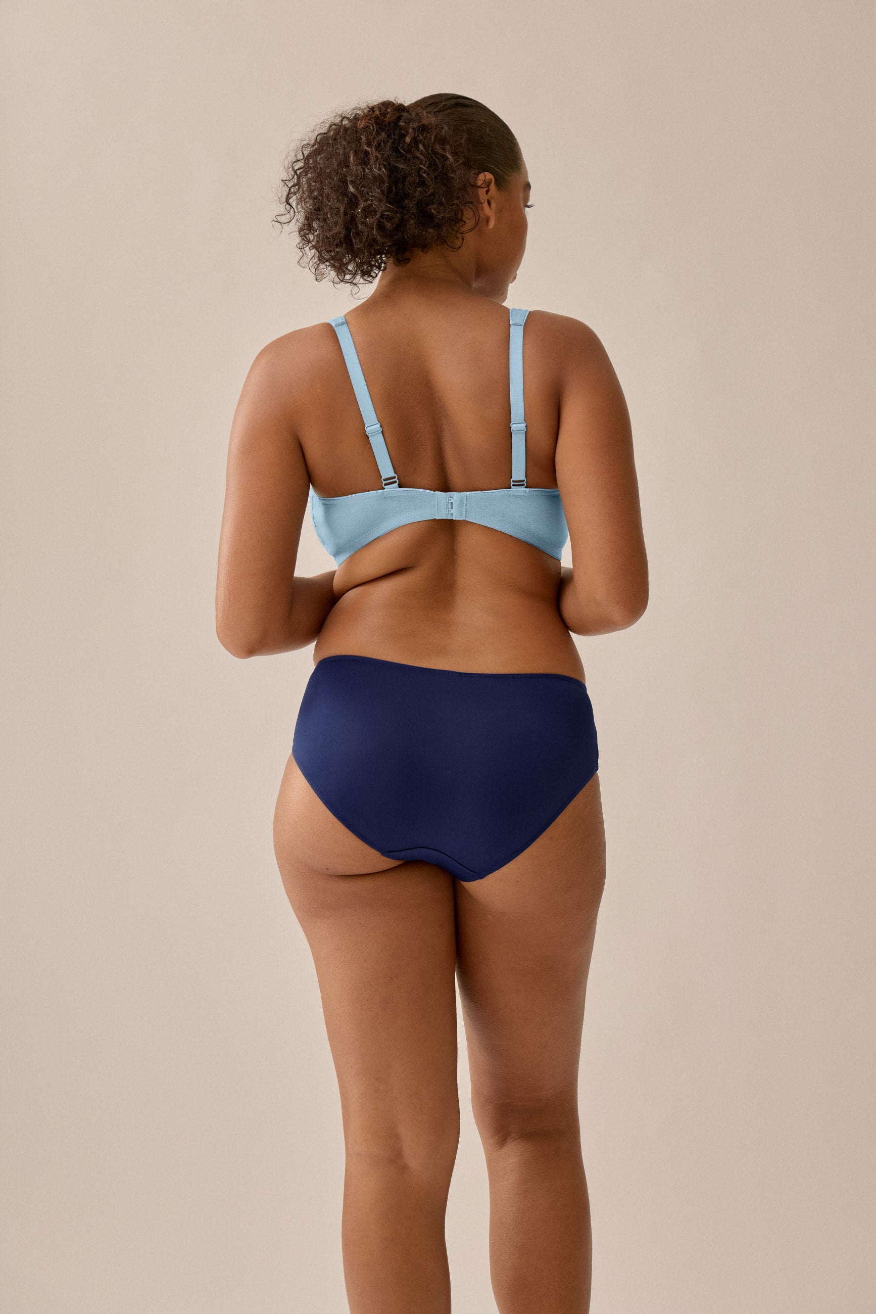 Photo of model wearing Naturana's Soft Cotton Bra in Matcha Sorbet with an angle from the back