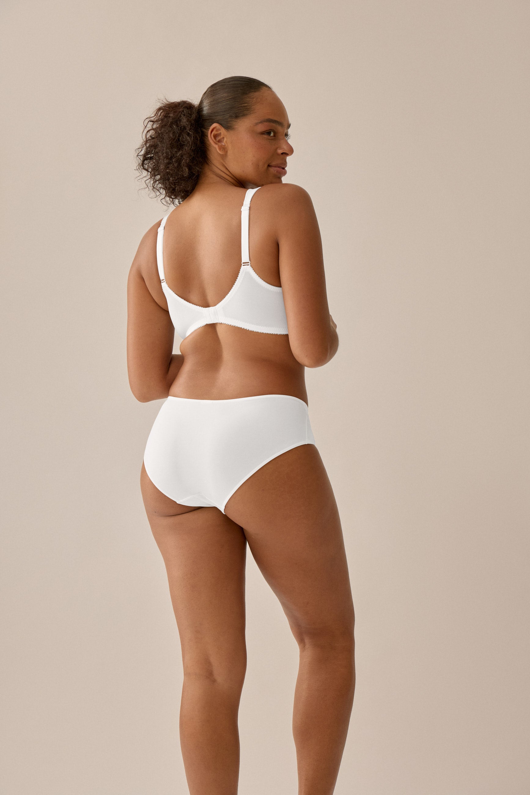 Model trägt weißen NATURANA Soft-BH mit Schalen und Entlastungsträgern. Rück Ansicht.