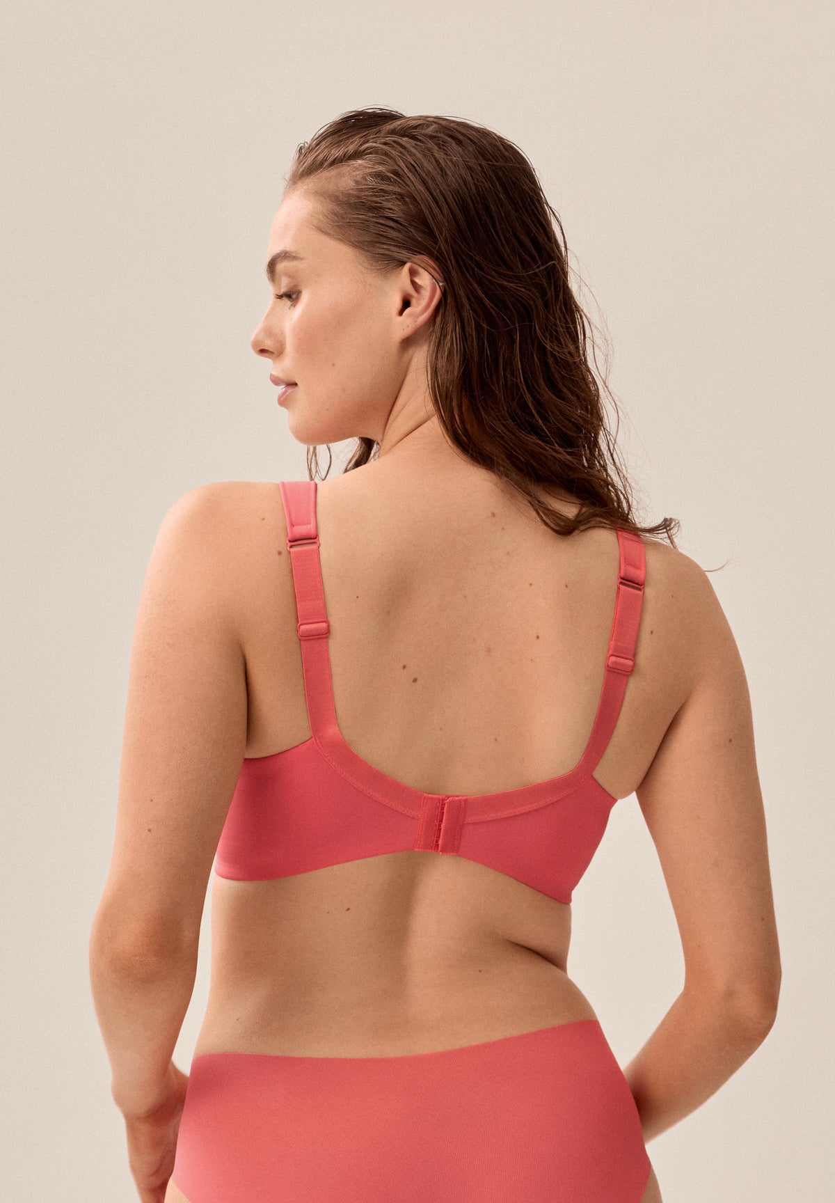 Korallpinker bügelloser NATURANA Soft-BH mit Schale und passender Panty, stehendes Model von hinten