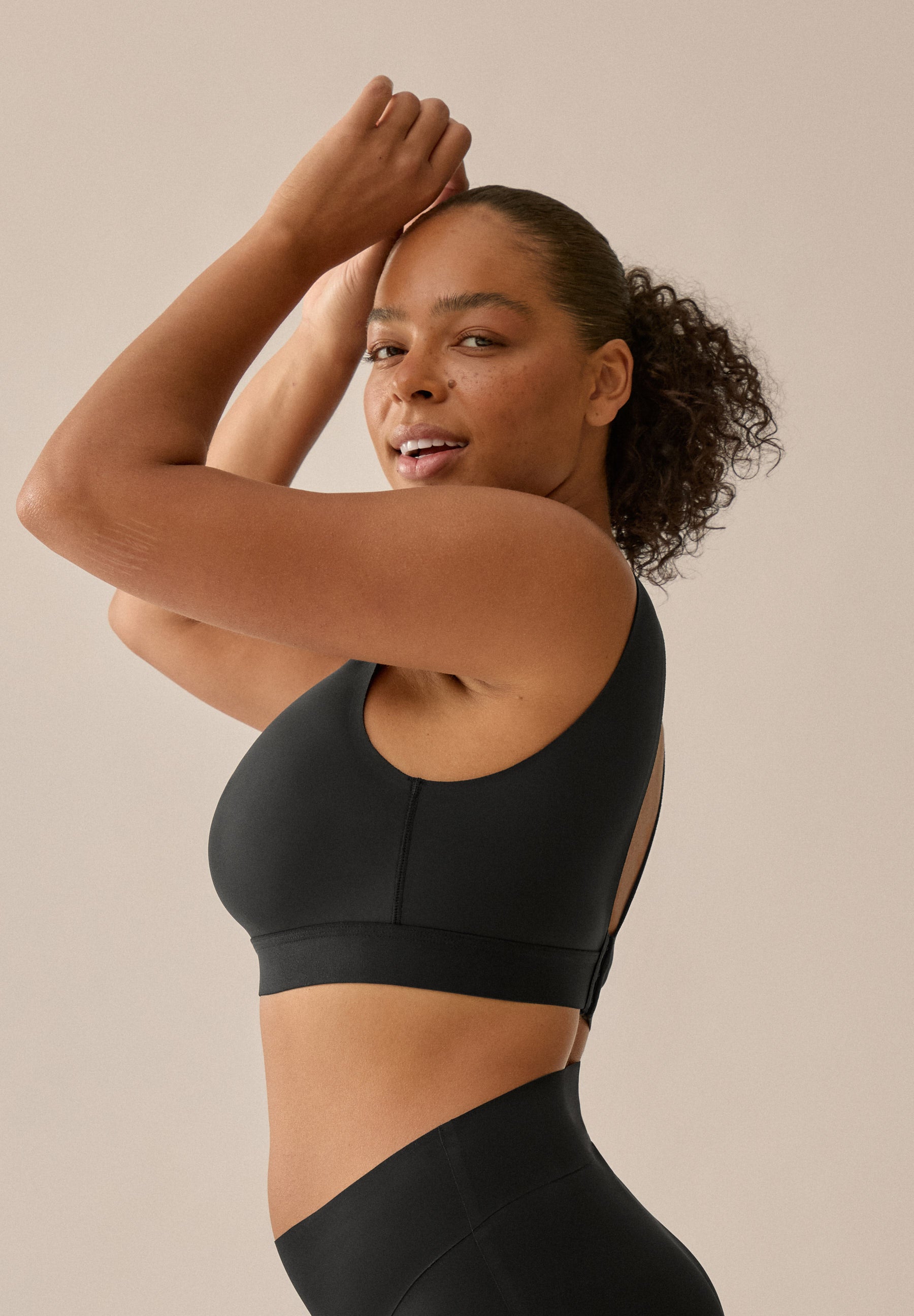 Model mit schwarzem BH und Slip aus der neuen glättenden BH-Kollektion von Naturana, mit Blick von links