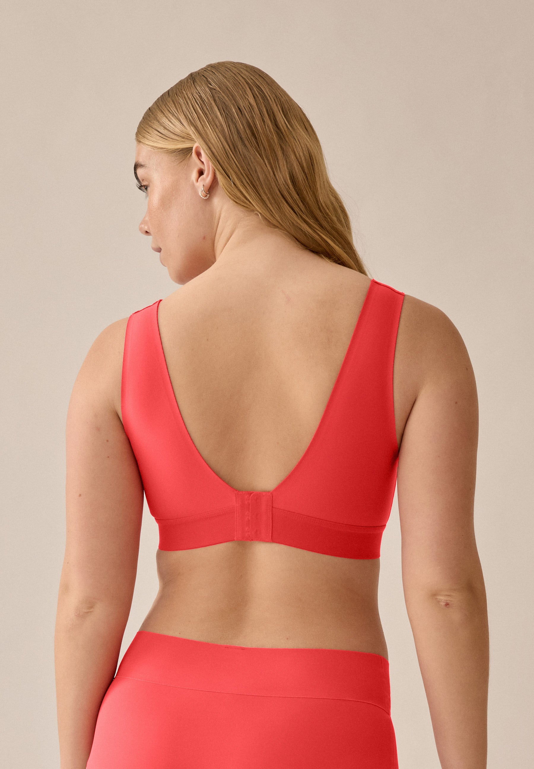 Model im Sitzen mit dem BH- und Slip-Set Chayenne Red von Naturana aus der neuen glättenden BH-Kollektion, mit Blickrichtung nach oben von hinten