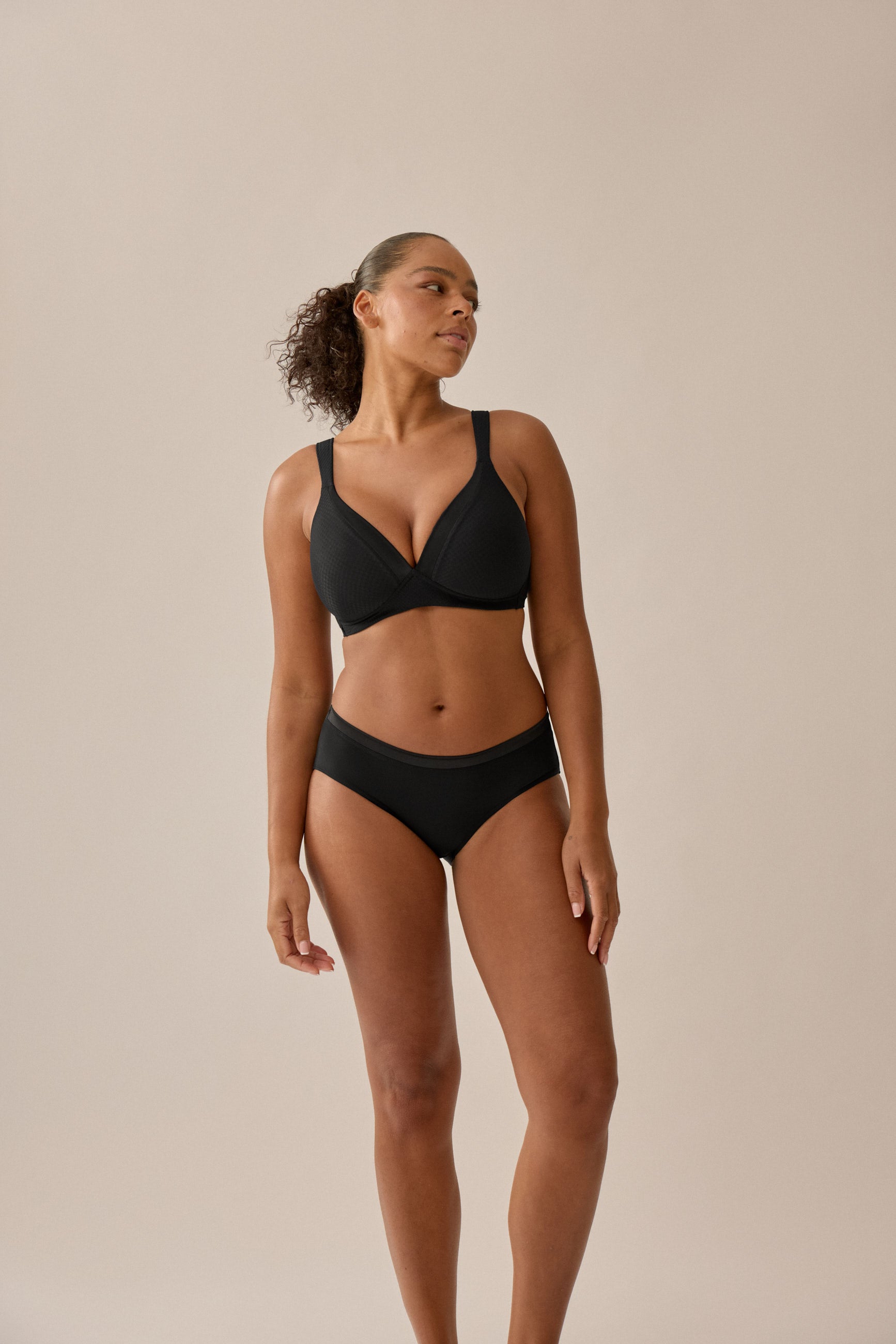 Foto des Models, das das schwarze BH- und Slip-Set von Naturana mit Jacquard-Muster trägt, mit einem Winkel von vorne