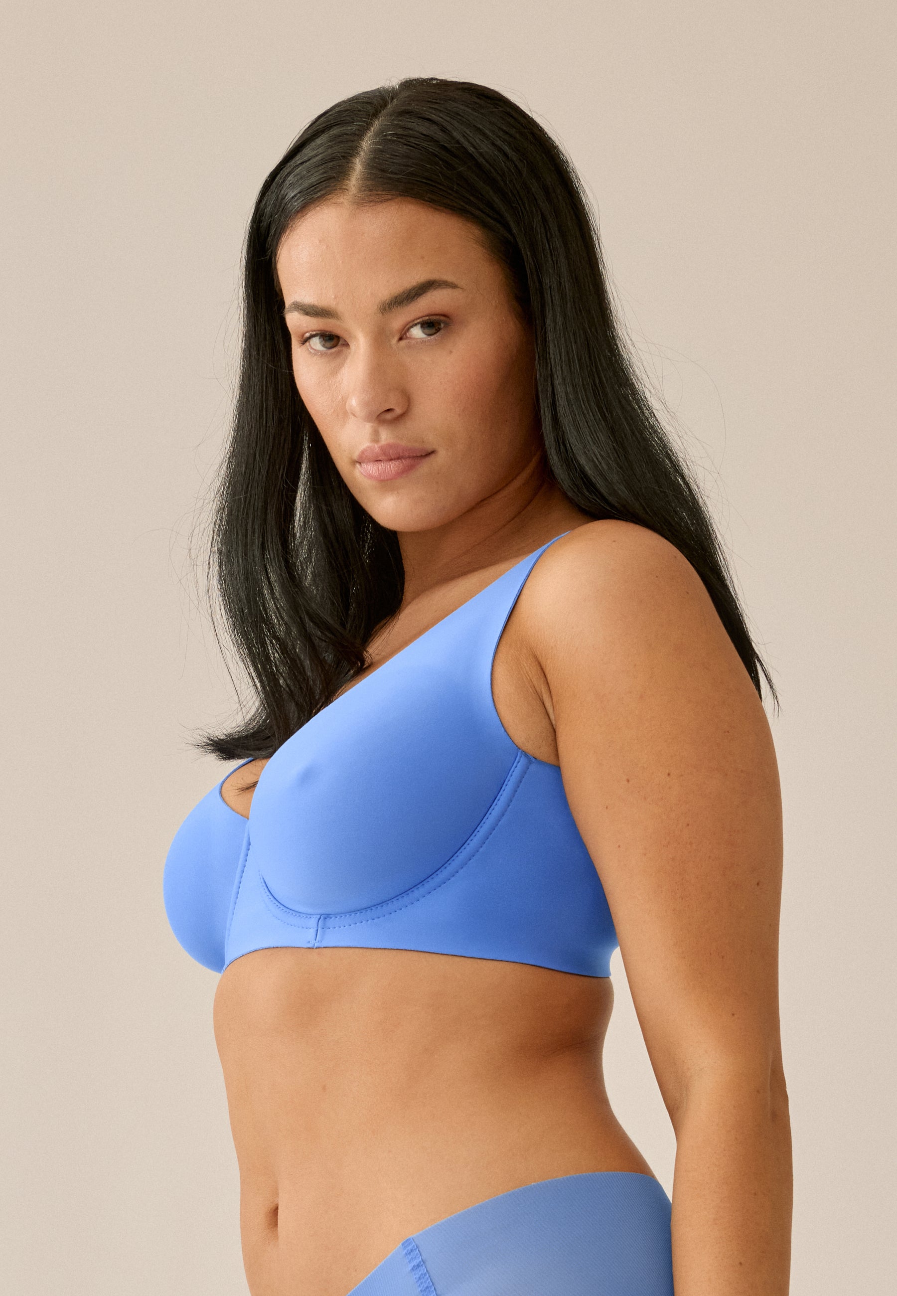 Model steht in Seitenansicht, trägt NATURANA Backsmoother BH mit Bügel und Panty in der Farbe "marina blue"