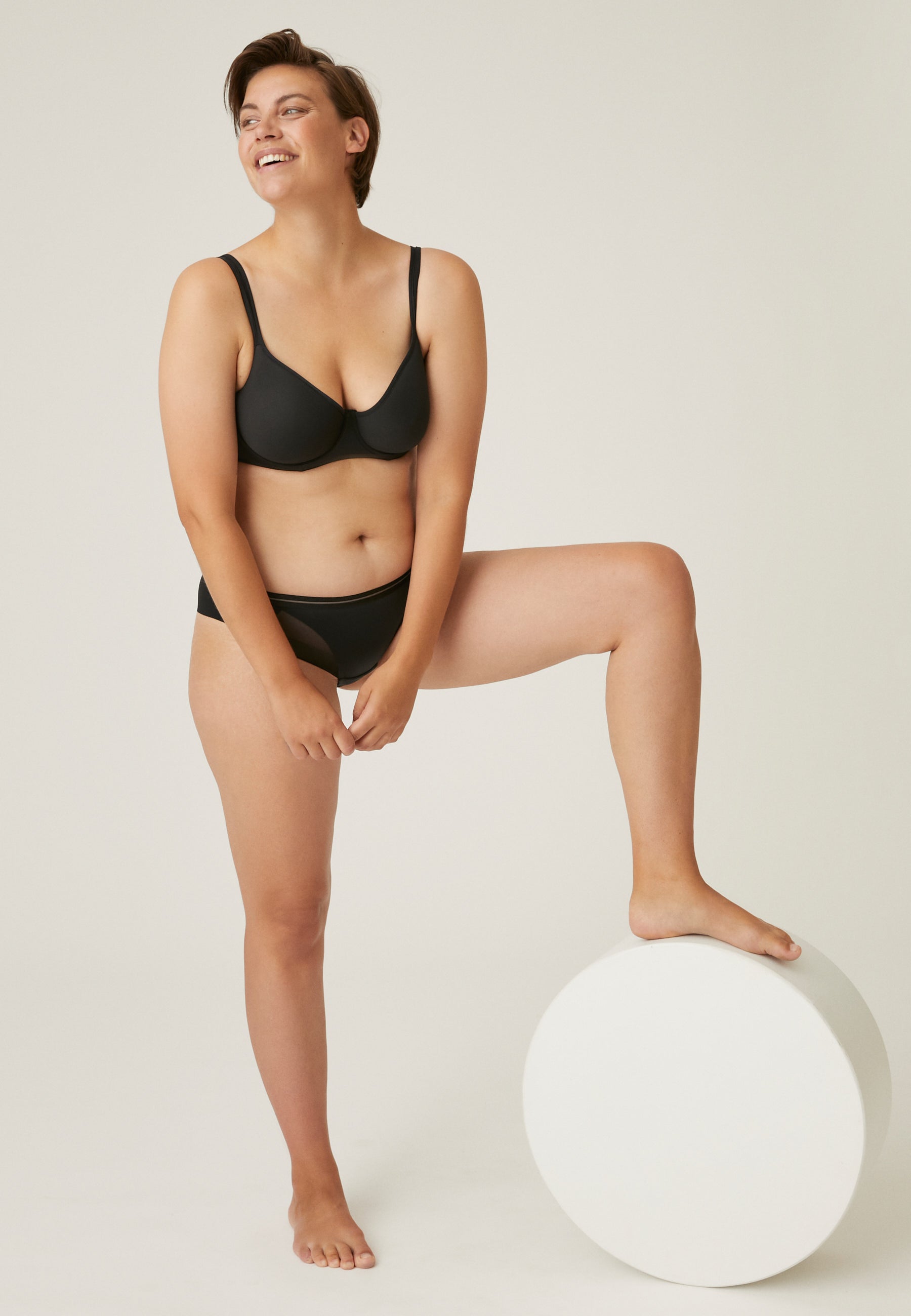 Model posiert im Naturana Monday Spacer Bügel-BH mit Mesh Details in der Farbe Schwarz