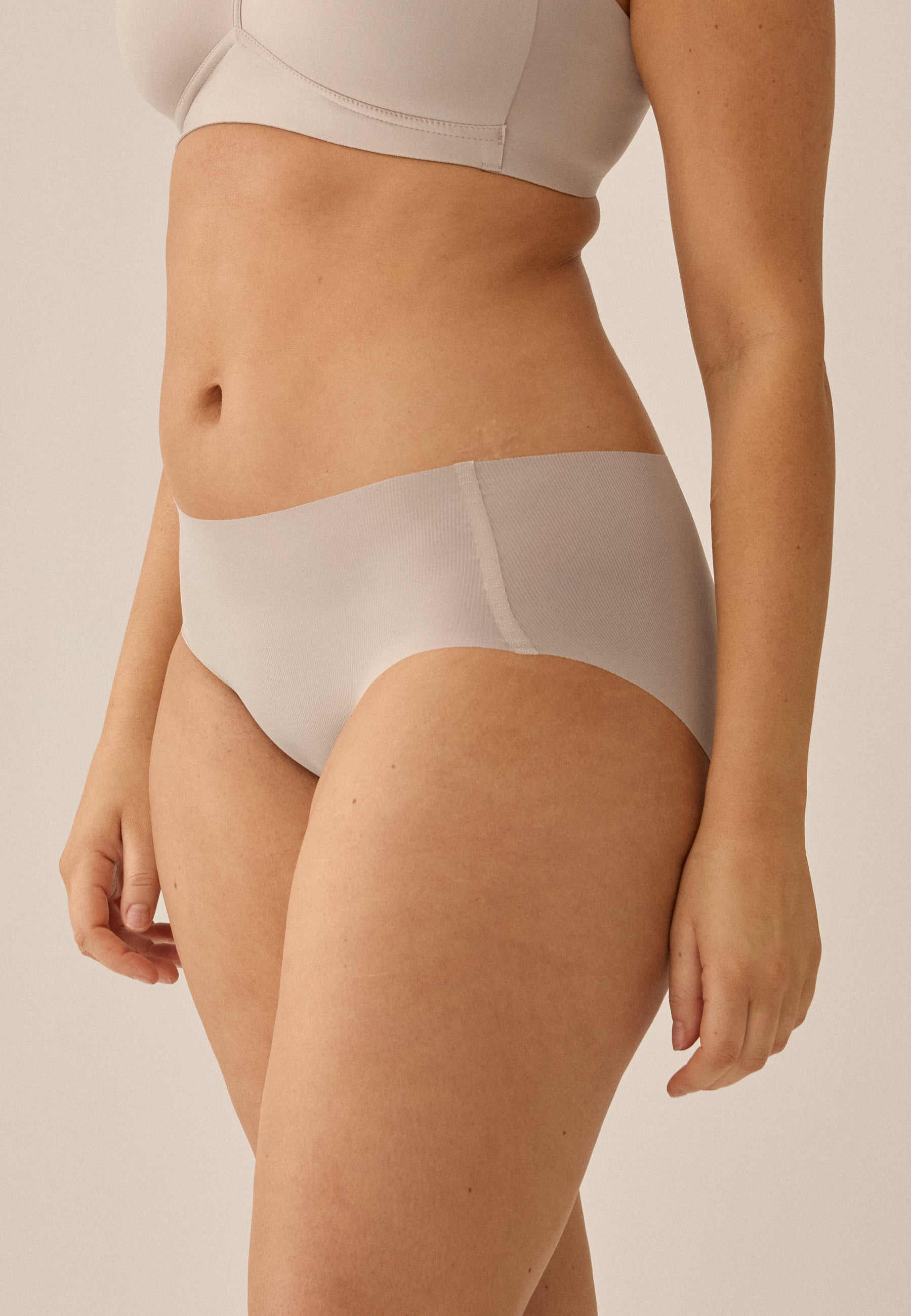 Model trägt NATURANA Everyday Slip und BH in der Farbe light beige, stehend in Seitenansicht in Nahaufnahme