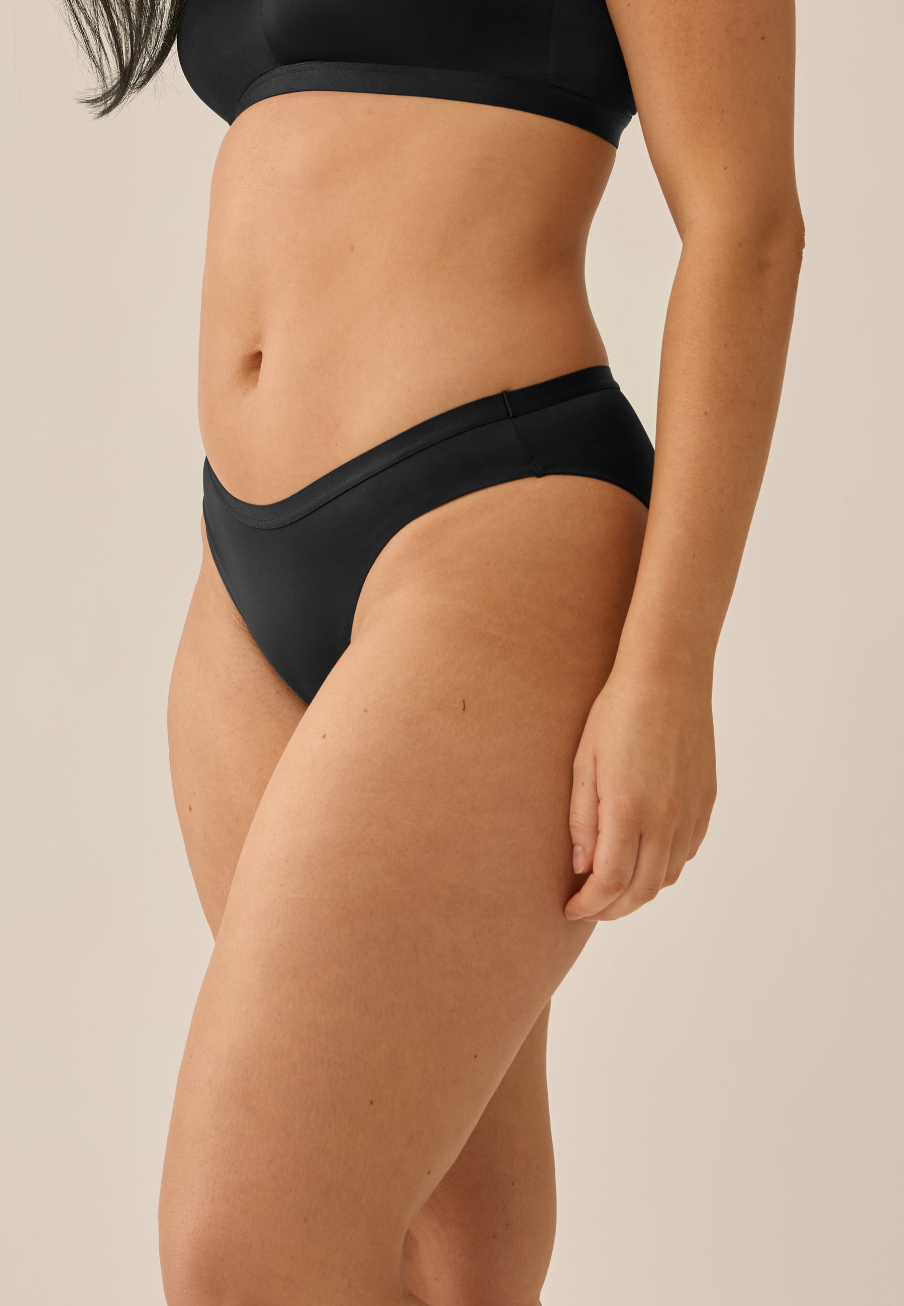 Model steht in NATURANA BH mit Bügel und Slip in der Farbe schwarz