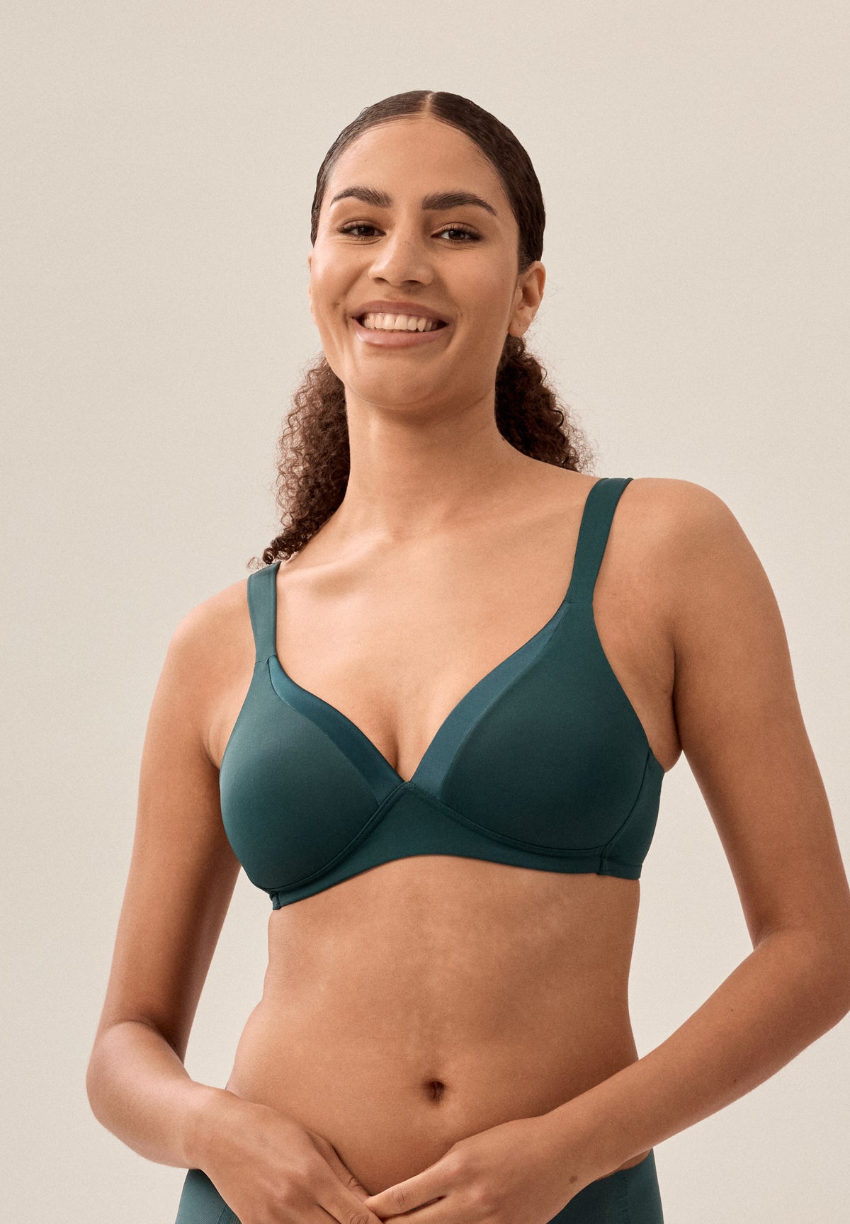 Tannengrüner bügelloser NATURANA Schalen-BH mit glänzendem Band am Ausschnitt und passender Panty, Model von vorne in Nahaufnahme