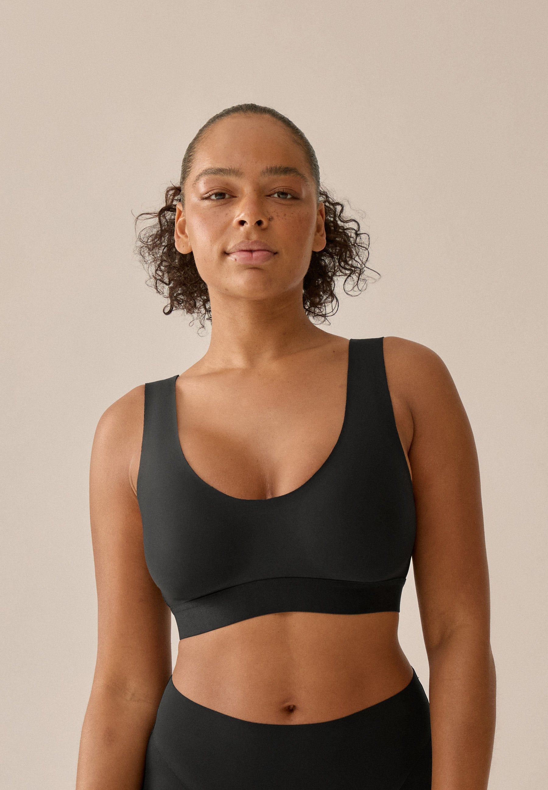 Model mit schwarzem BH und Slip aus der neuen glättenden BH-Kollektion von Naturana, mit Blickwinkel von vorne