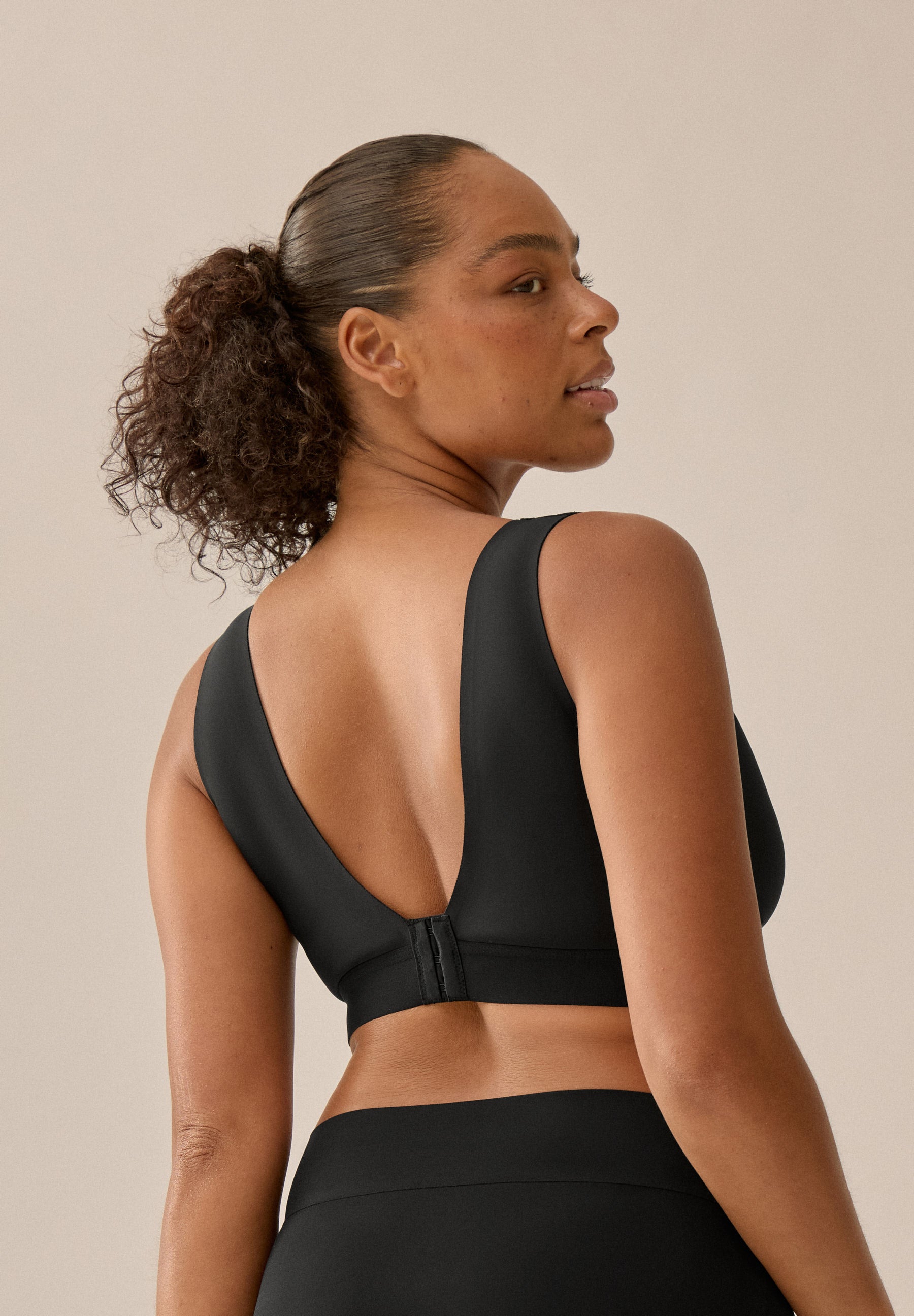 Model mit schwarzem BH und Slip aus der neuen glättenden BH-Kollektion von Naturana, mit Blick auf den Rücken